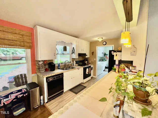 a large kitchen with stainless steel appliances a stove a sink dishwasher and a refrigerator with wooden floor