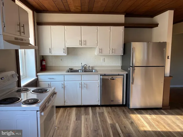 a kitchen with a sink a refrigerator and white cabinets