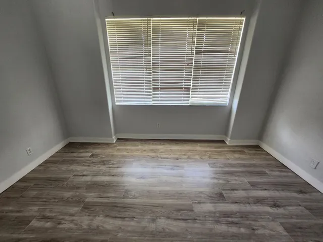 a view of empty room with window and wooden floor