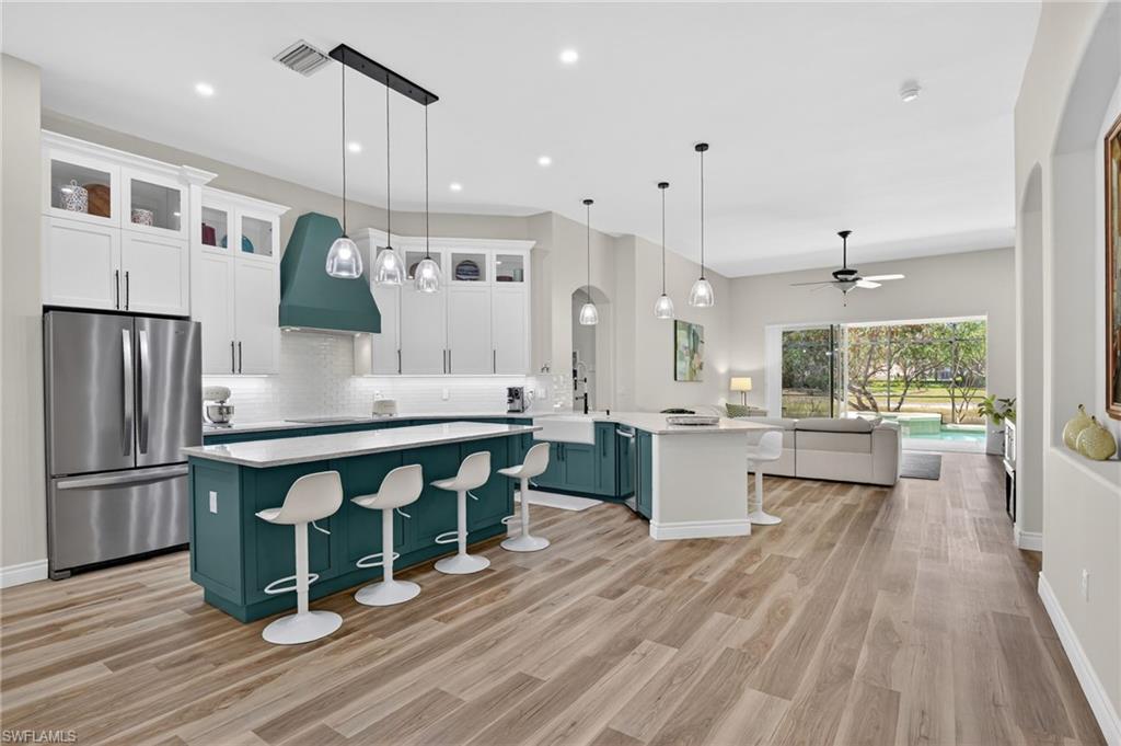 a kitchen with stainless steel appliances granite countertop a refrigerator a sink dishwasher a stove and white countertops with wooden floor