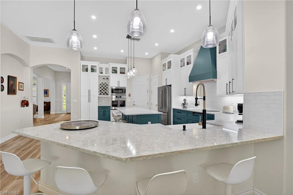 2065 Mandarin Lane Naples, FL 34120 - Photo 20 of 46 a kitchen with stainless steel appliances granite countertop a sink a stove a refrigerator and chairs