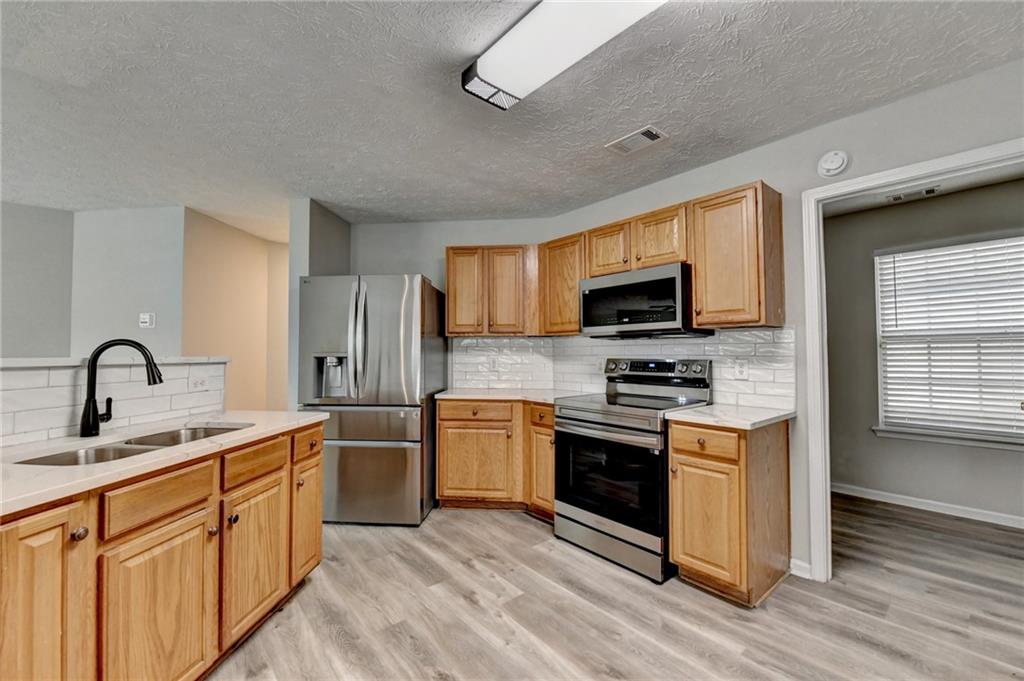 2748 Farmstead Court Grayson, GA 30017 - Photo 37 of 83 a kitchen with stainless steel appliances granite countertop a stove top oven a sink dishwasher a refrigerator and a microwave oven with wooden floor