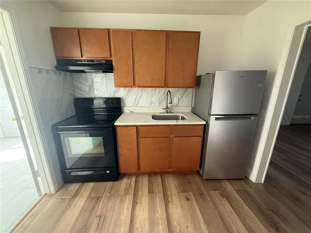 a kitchen with a sink a refrigerator and cabinets