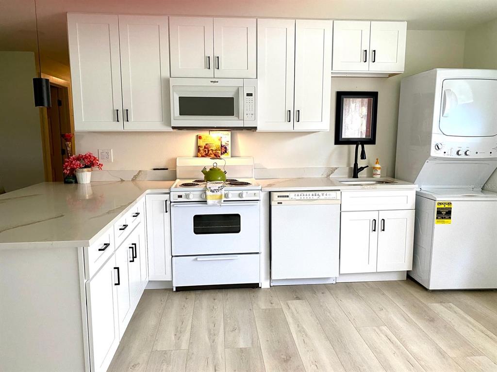 415 Mapleway, Unit A Safety Harbor, FL 34695 - Photo 15 of 50 a kitchen with white cabinets sink and white appliances