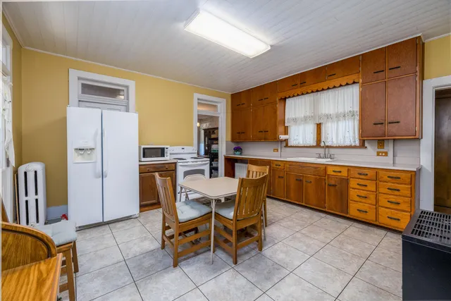 a kitchen with a dining table chairs and a refrigerator