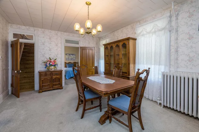a view of a dining room with furniture a chandelier and window