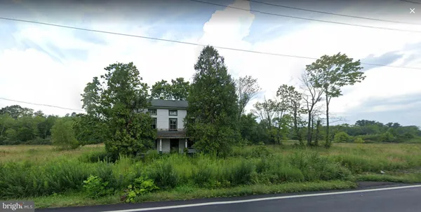 a view of a house in a big yard with plants and large trees