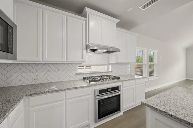 an empty room with wooden floor ceiling fan and windows
