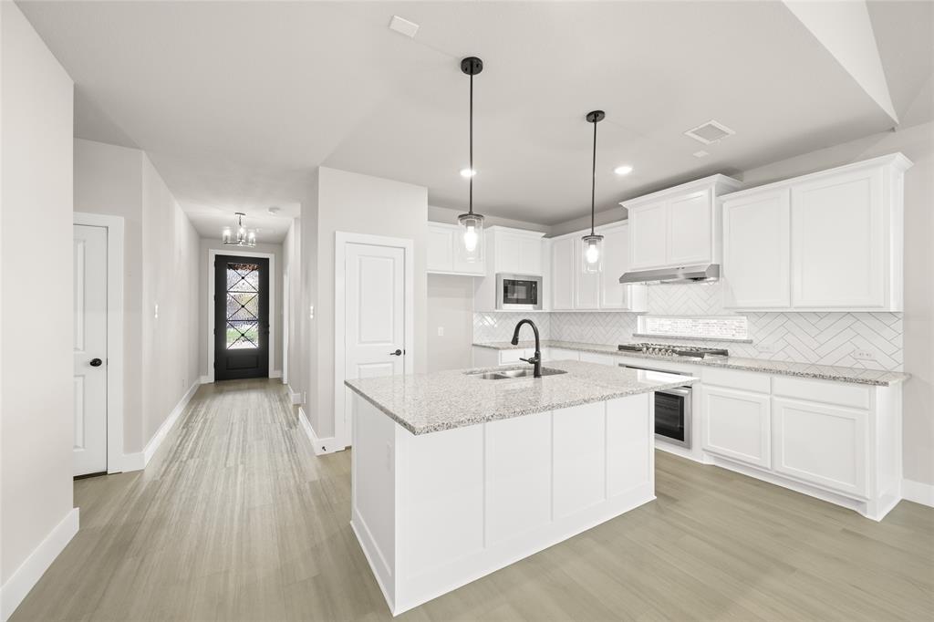 1850 Silver Birch Road Waxahachie, TX 75165 - Photo 9 of 36 a kitchen with kitchen island a sink stove and refrigerator