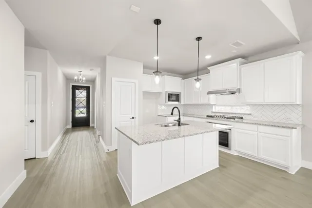 a kitchen with granite countertop a sink stove and cabinets