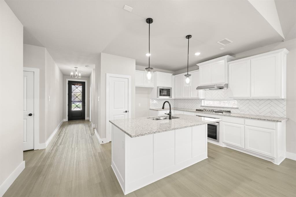 1850 Silver Birch Road Waxahachie, TX 75165 - Photo 10 of 36 a kitchen with kitchen island a sink stove and refrigerator