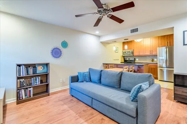 a living room with furniture kitchen view and wooden floor