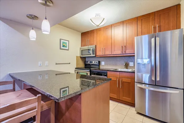 a kitchen with stainless steel appliances a refrigerator a stove a sink a center island and cabinets