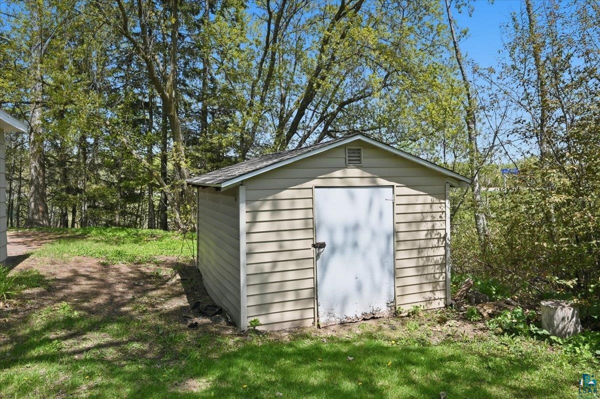 5319 East 3rd Street Superior, WI 54880 - Photo 33 of 33 Exterior storage shed featuring tan horizontal siding, a white metal door, and a shingled gable roof