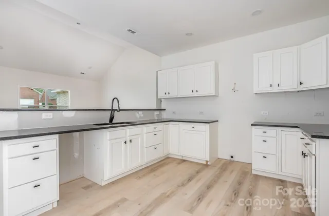 a kitchen with cabinets appliances a sink and dishwasher with wooden floor