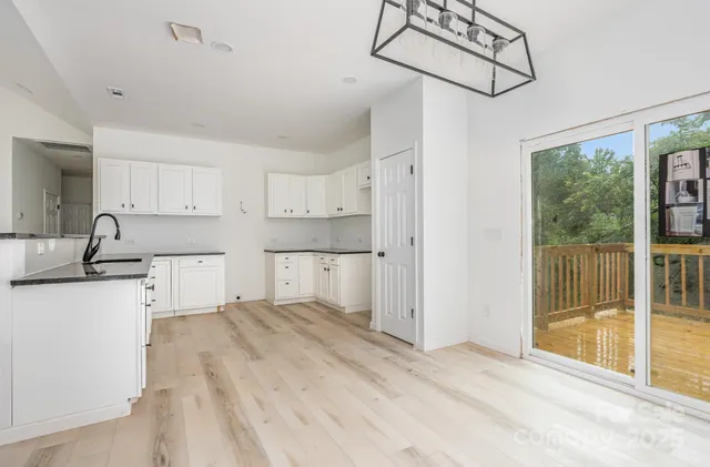 a kitchen with stainless steel appliances granite countertop a refrigerator a sink and white cabinets