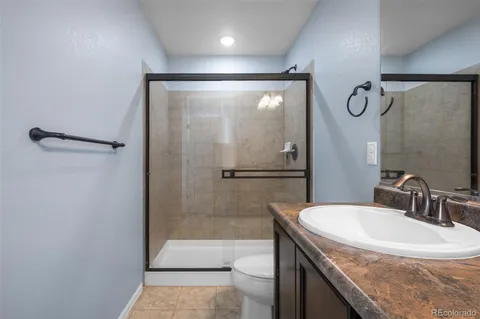 a bathroom with a granite countertop sink a mirror and a shower