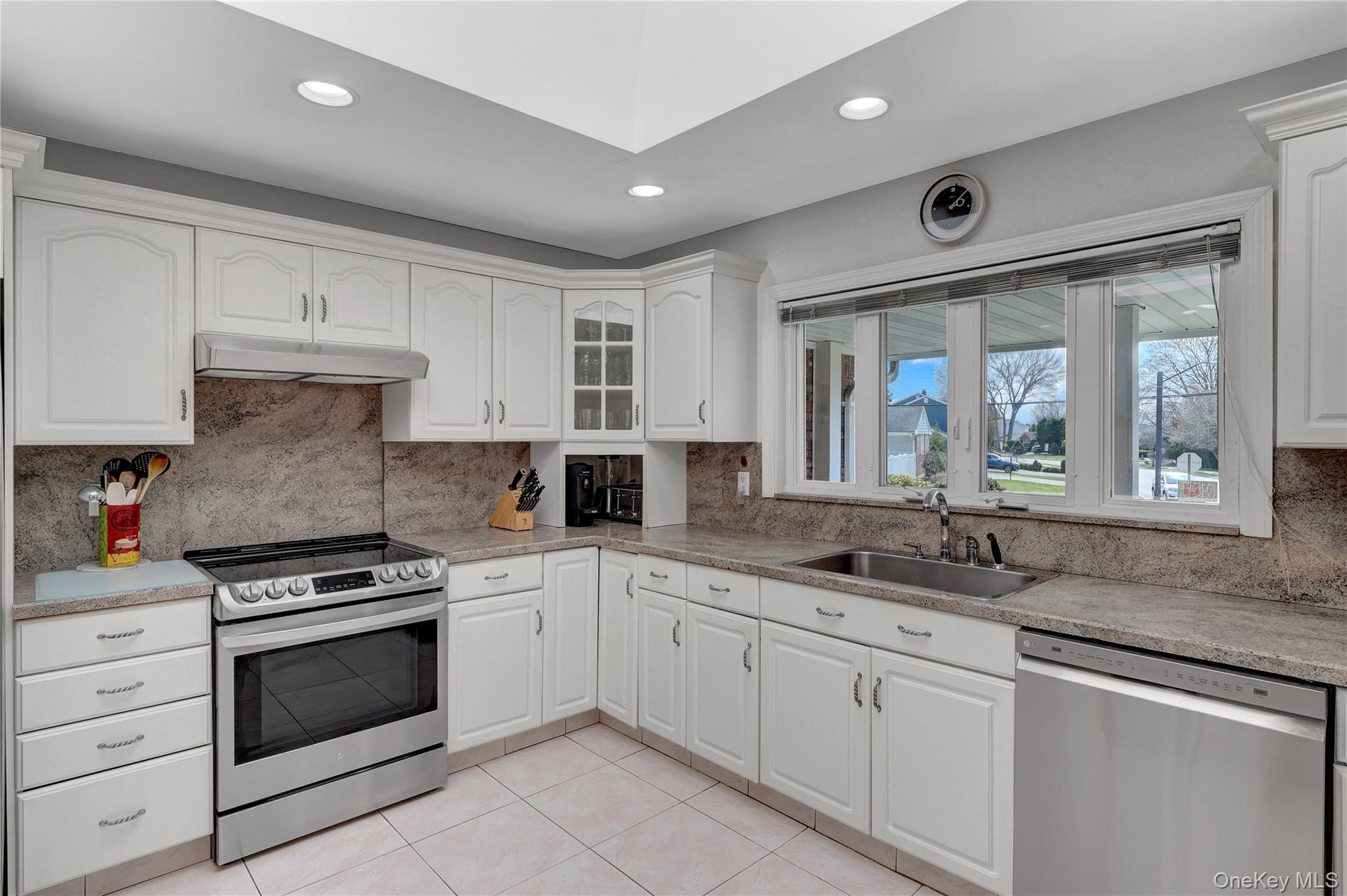 27 Cedar Street Syosset, NY 11791 - Photo 11 of 28 a kitchen with granite countertop a sink stainless steel appliances and white cabinets