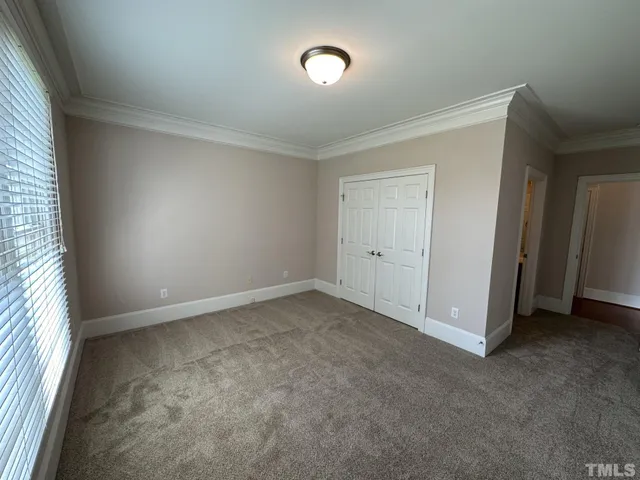 an empty room with chandelier fan and windows