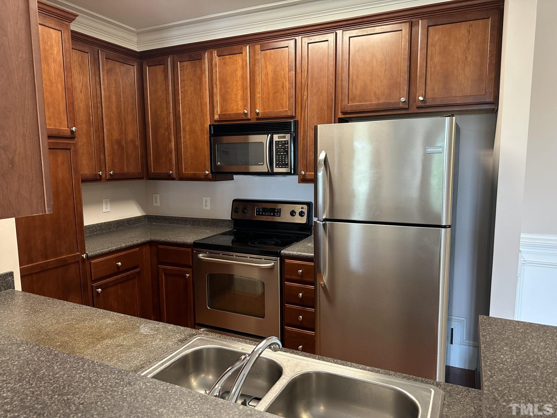 623 Waterford Lake Drive, Unit 623 Cary, NC 27519 - Photo 8 of 18 a kitchen with granite countertop wooden cabinets and a refrigerator