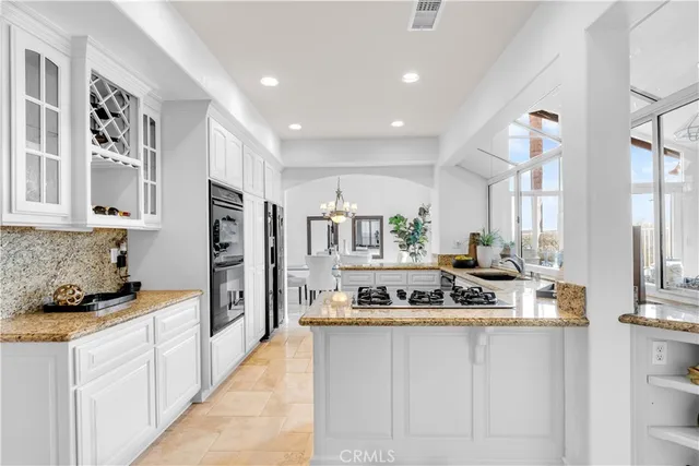 a kitchen with kitchen island granite countertop stainless steel appliances a stove refrigerator sink and cabinets