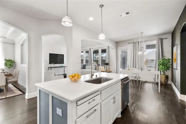 a kitchen with stainless steel appliances a stove a sink a refrigerator and white cabinets with wooden floor