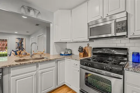 a kitchen with cabinets stainless steel appliances a sink and a stove