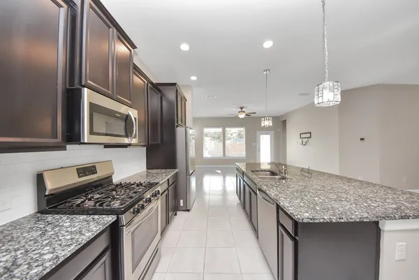 a kitchen with granite countertop stainless steel appliances and refrigerator