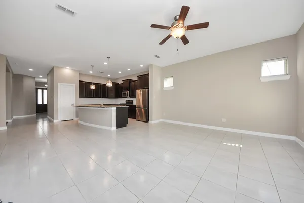 a view of a livingroom with a ceiling fan and kitchen space with a sink