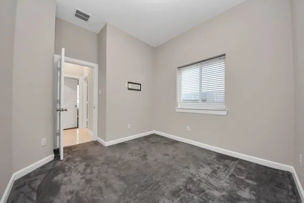 a view of an empty room with closet and a window