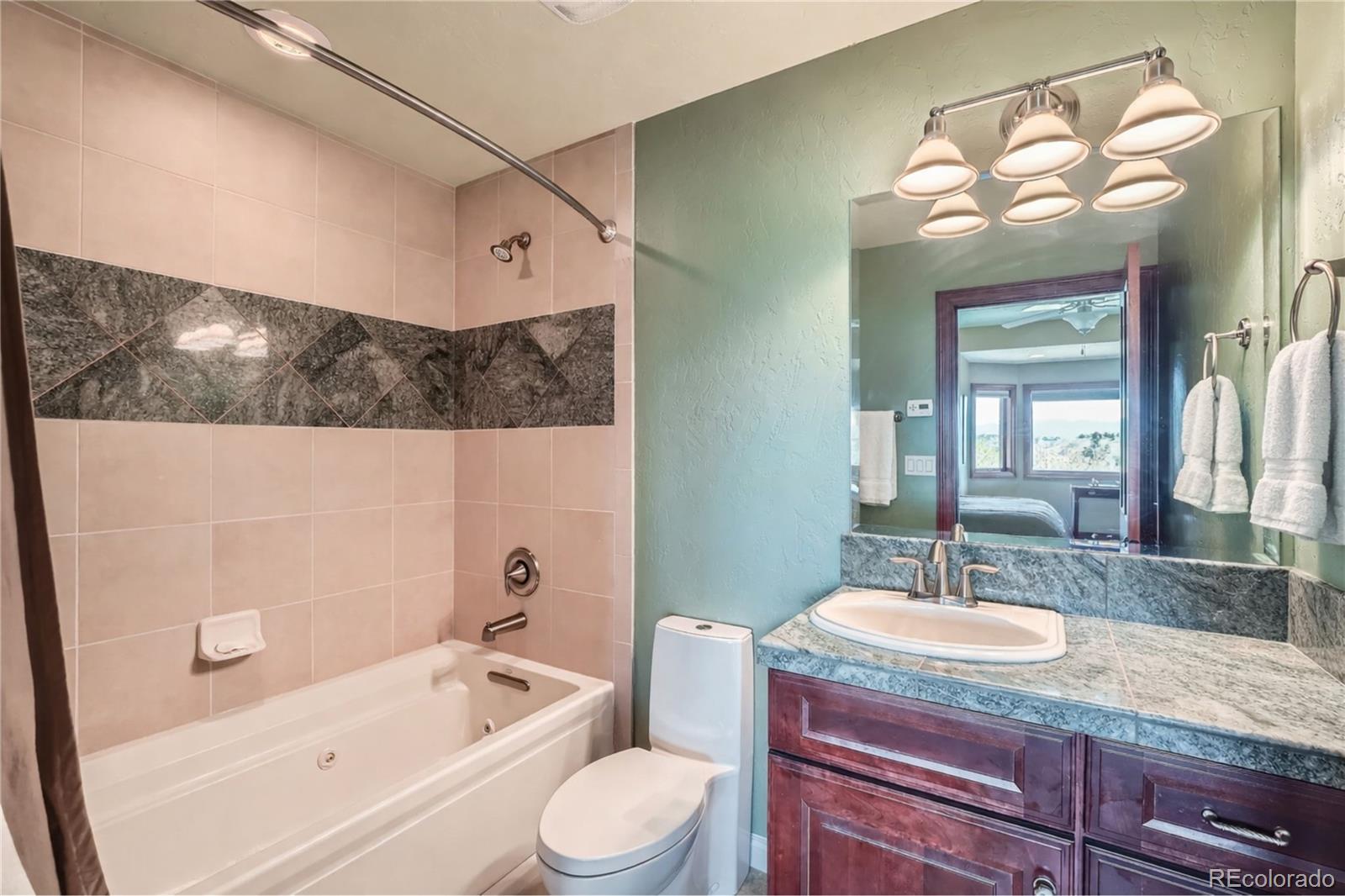 401 Raptor Point Golden, CO 80403 - Photo 37 of 44 a bathroom with a granite countertop sink a toilet a mirror and bathtub