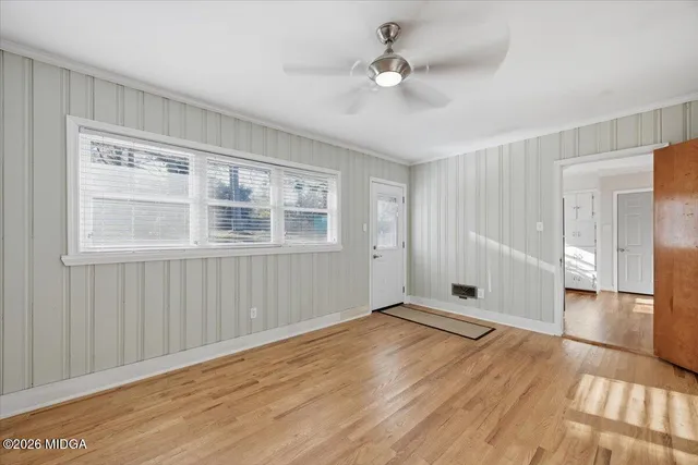 a view of empty room with wooden floor and fan