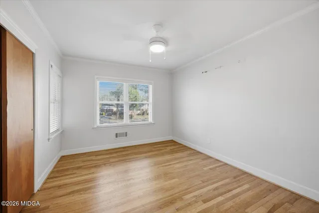 a view of empty room with wooden floor and fan