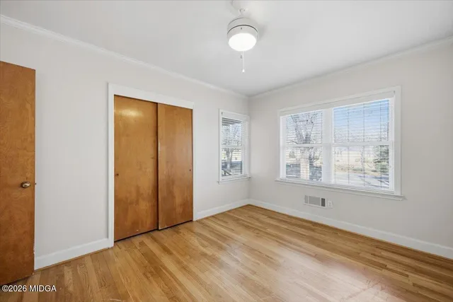 a view of empty room with wooden floor and fan