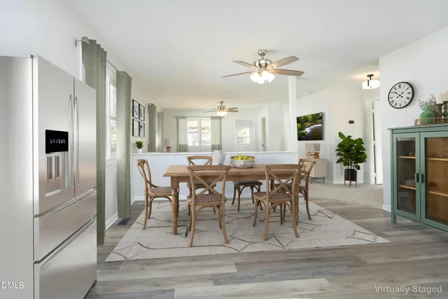 a view of a livingroom with a fireplace a ceiling fan and wooden floor