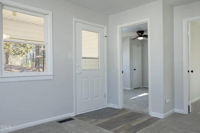 an empty room with a kitchen and a ceiling fan