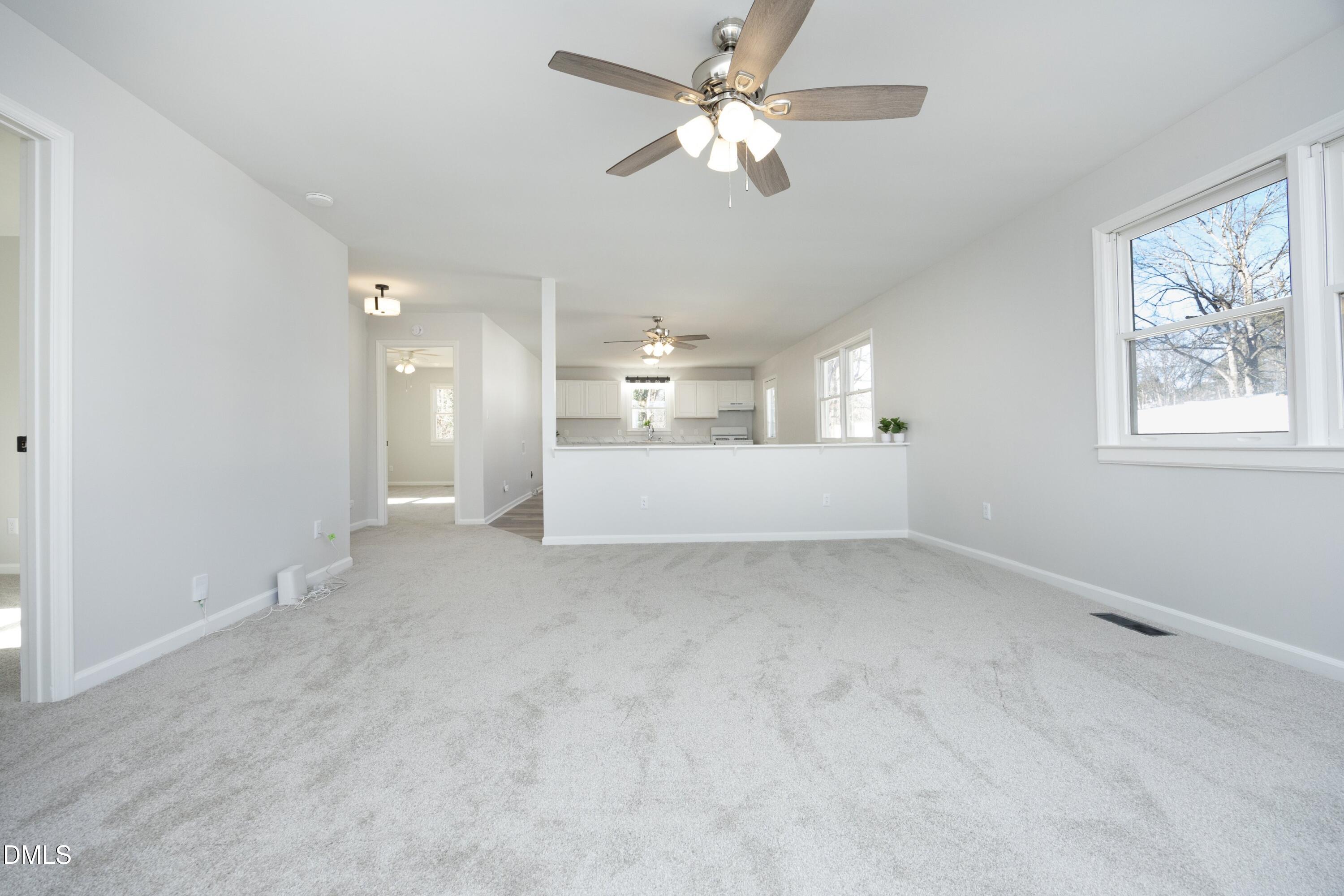 5108 Old Valley Street Raleigh, NC 27603 - Photo 8 of 37 an empty room with a kitchen and a ceiling fan