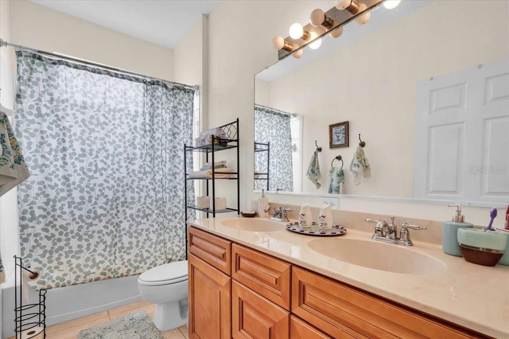 15688 Lemon Fish Drive Lakewood Ranch, FL 34202 - Photo 11 of 18 a bathroom with a granite countertop sink a toilet and a shower curtain