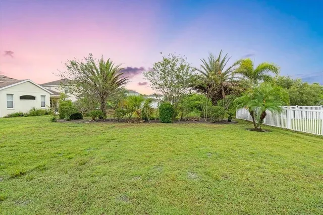 a palm tree sitting in front of a house with a big yard