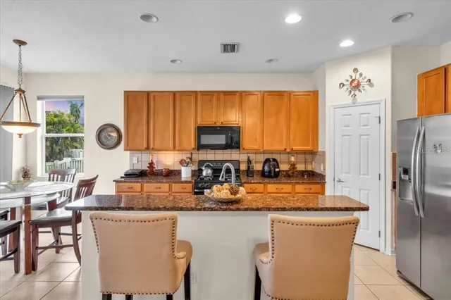 a kitchen with stainless steel appliances granite countertop a refrigerator a stove top oven a sink dishwasher and white cabinets with wooden floor