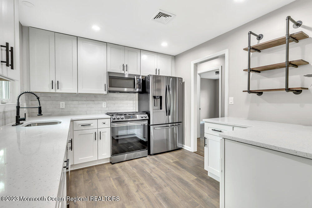28 Maplecrest Drive Neptune Township, NJ 07753 - Photo 5 of 20 a kitchen with a sink a refrigerator and a stove top oven with wooden floor
