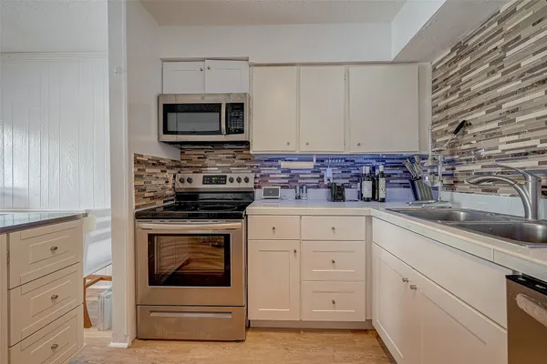 a kitchen with white cabinets stainless steel appliances and sink