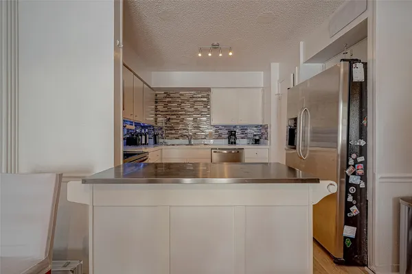 a close view of kitchen with stainless steel appliances granite countertop a sink and a refrigerator