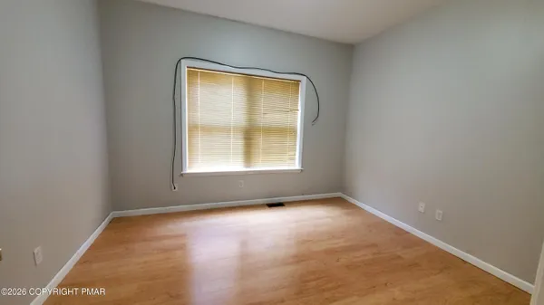 an empty room with chandelier fan and windows