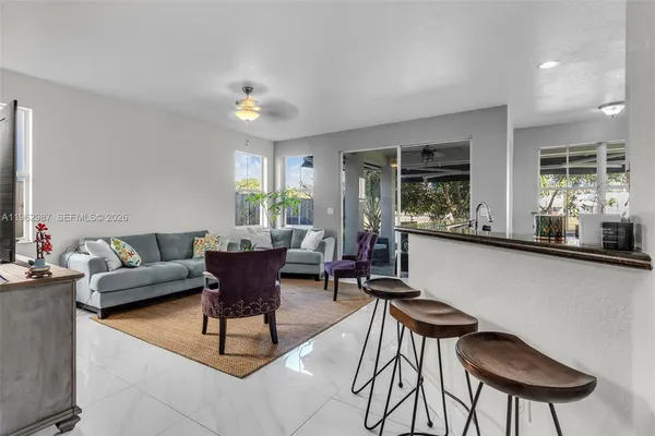 a living room with furniture a chandelier and a dining table with a kitchen view