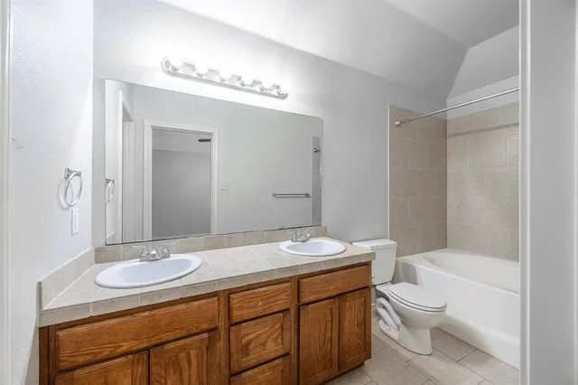 a bathroom with a granite countertop sink a toilet a mirror and shower