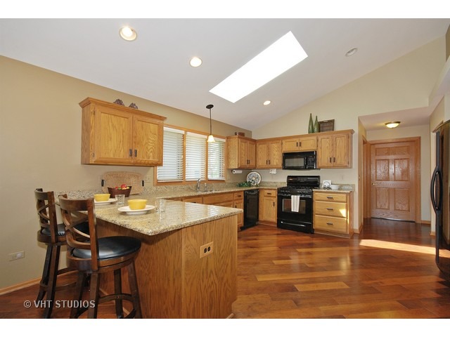 4N575 School Road St. Charles, IL 60175 - Photo 3 of 20 a kitchen with stainless steel appliances kitchen island granite countertop a table chairs and a refrigerator