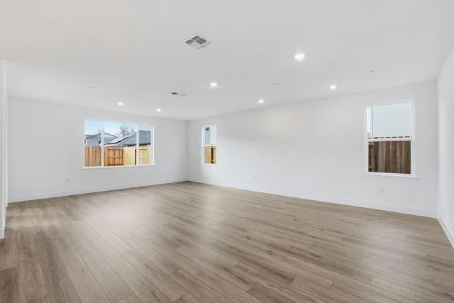 a view of an empty room with wooden floor and windows