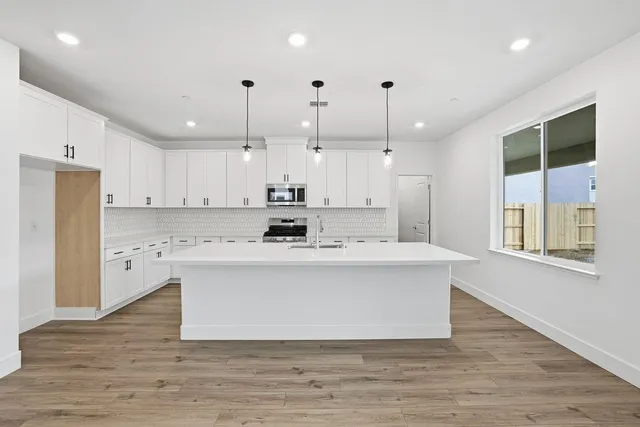 a large kitchen with kitchen island a sink a center island stainless steel appliances and a window