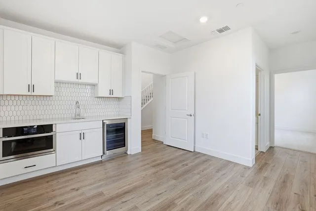 a kitchen with granite countertop wooden floors stainless steel appliances and white cabinets